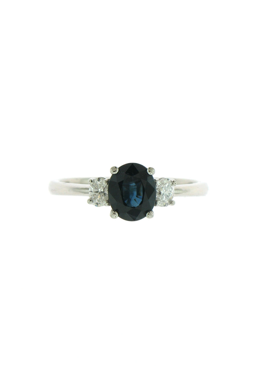 A custom made platinum and diamond 3-stone ring with a dark blue sapphire and 2 oval diamonds on the side.