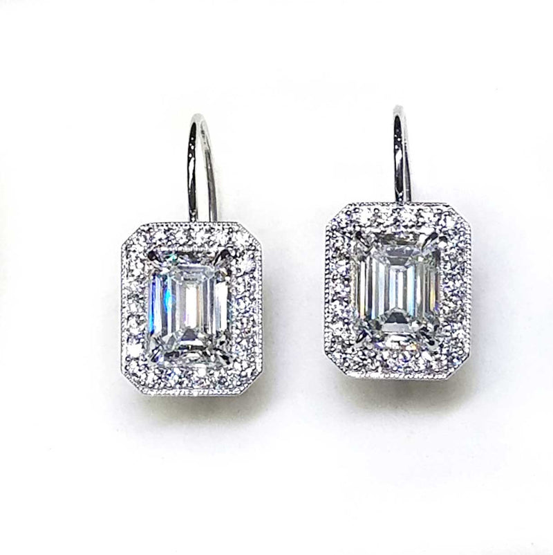 Emerald cut diamond drop earrings surrounded with a halo of diamonds.