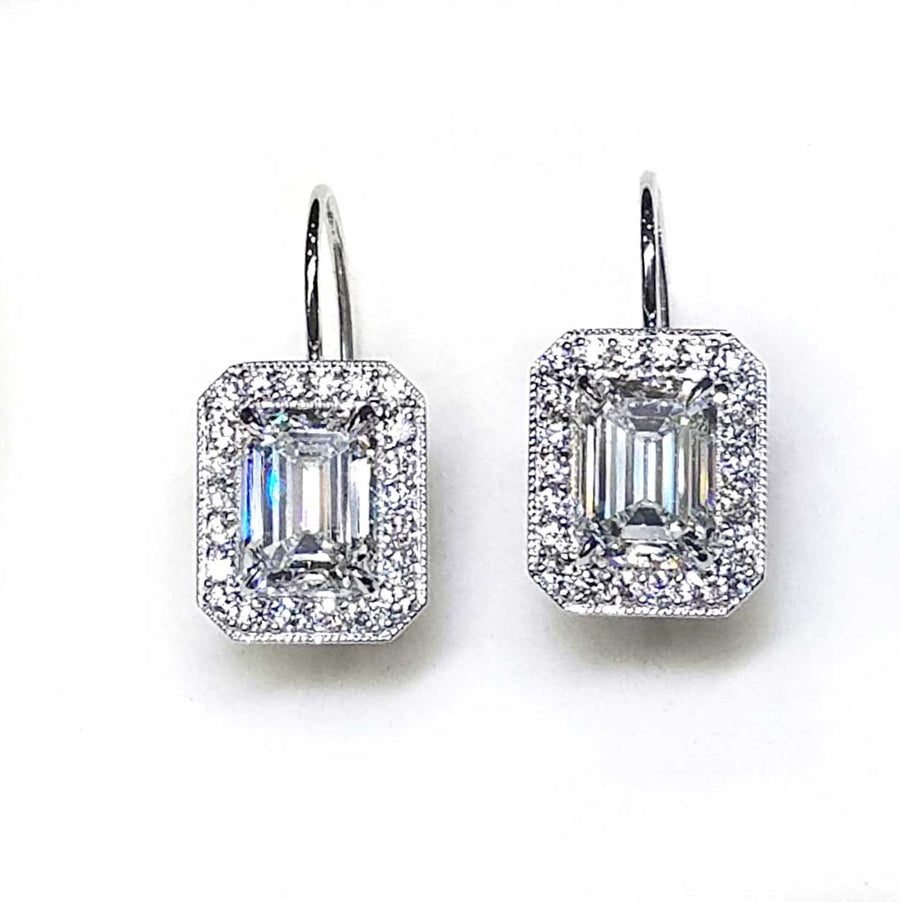 Emerald cut diamond drop earrings surrounded with a halo of diamonds.